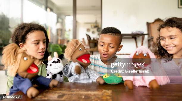 des enfants souriants qui jouent ensemble avec des marionnettes à main - puppeteer photos et images de collection
