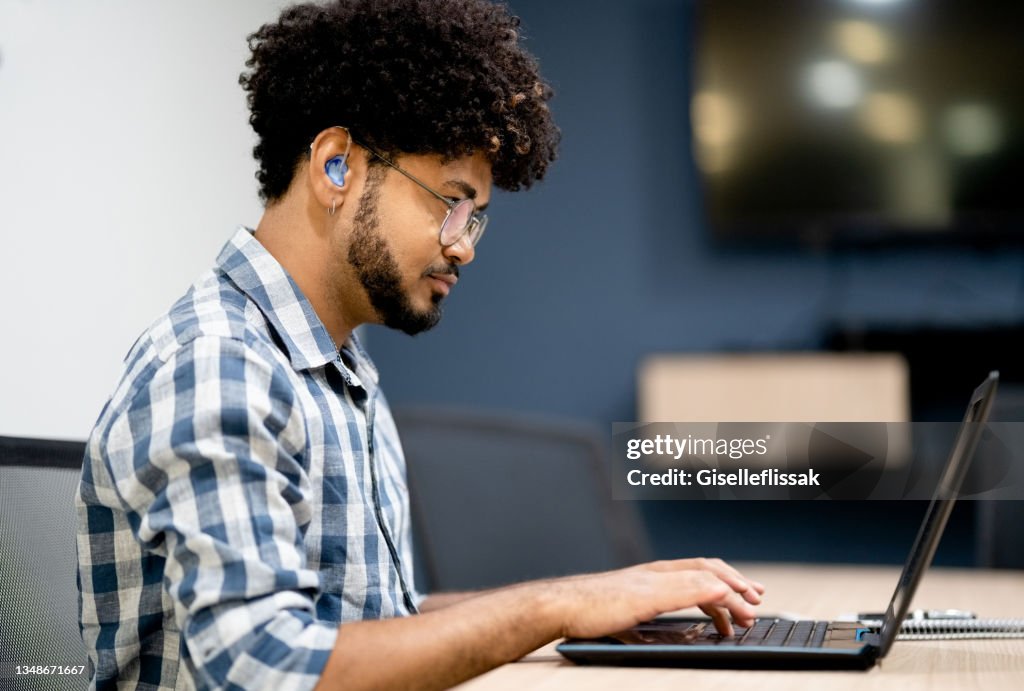 Uomo con problemi di udito che lavora sul laptop in ufficio