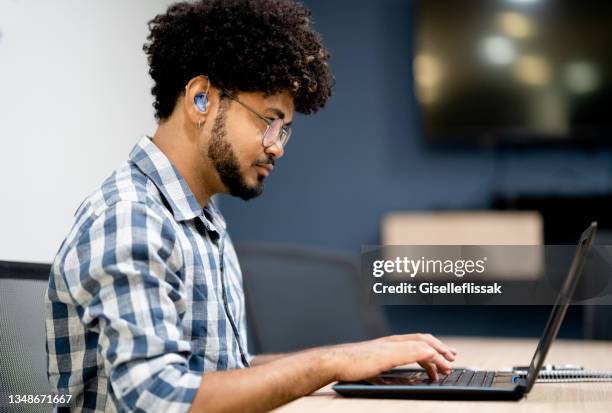 hearing impaired man working on laptop at office - disability bildbanksfoton och bilder