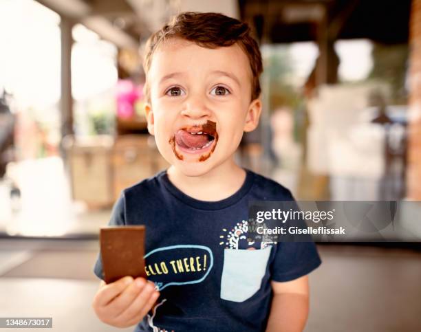 smiling little boy licking messy chocolate from his face - chocolat 個照片及圖片檔