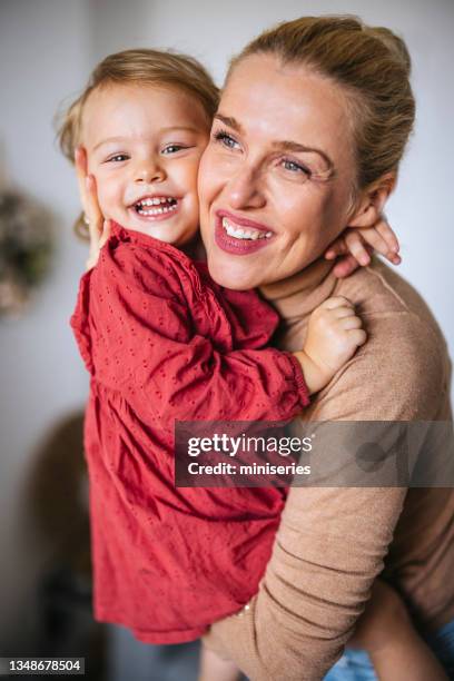 cheerful mother embracing her daughter at home - blond stock pictures, royalty-free photos & images