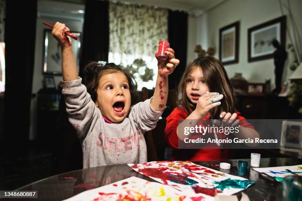 two little girls painting in home and playing. domestic images - family drawing stock-fotos und bilder