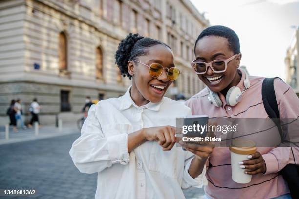 two woman in the city, looking at the phone and smiling - generation z on phone stock pictures, royalty-free photos & images