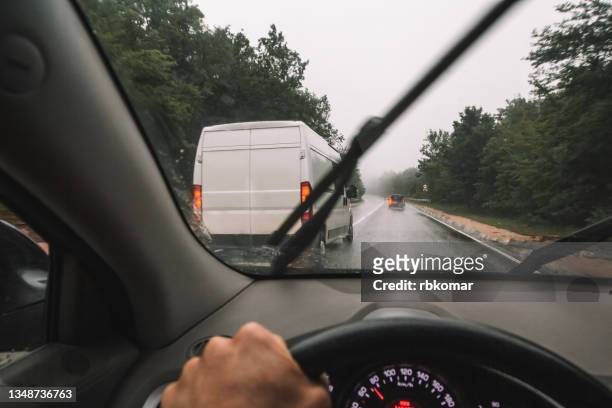 dangerous overtaking on a wet country road in rainy weather - ruitenwisser stockfoto's en -beelden