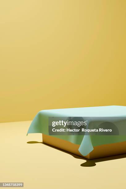 3d render of green cloth on top of orange table with yellow background, copy space - hector vivas fotografías e imágenes de stock