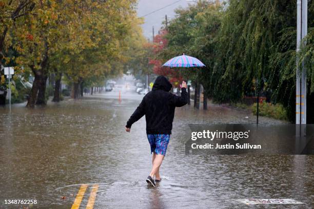 Pedestrian carries an umbrella as he walks on a flooded street on October 24, 2021 in San Rafael, California. A Category 5 atmospheric river is...