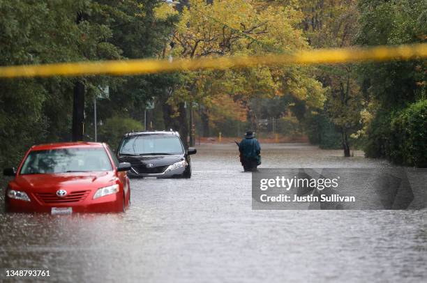 Pedestrian walks on a flooded street on October 24, 2021 in Kentfield, California. A Category 5 atmospheric river is bringing heavy precipitation,...