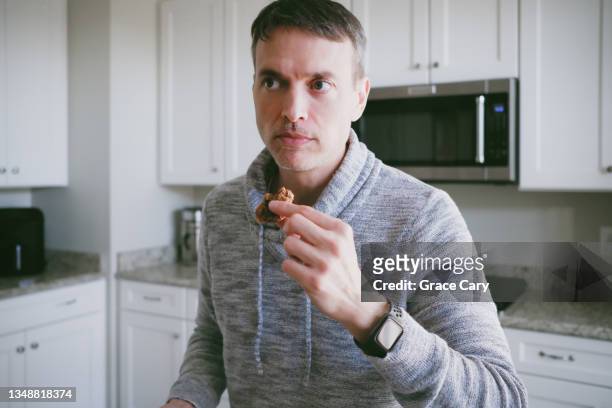 man snacks on cookie - chocolate eating stock pictures, royalty-free photos & images