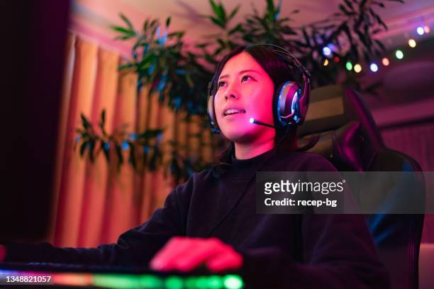 自宅のリビングルームでマルチプレイヤーオンラインゲームをプレイしながら、若い女性のライブストリーミング - ゲーマー ストックフォトと画像