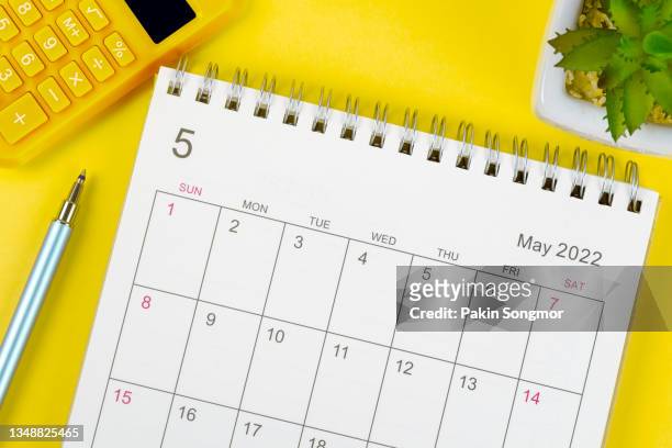 calendar desk 2022 on may month, top view calendar for organizer to planning and pen, calculator, houseplant on yellow background. - maifeiertag stock-fotos und bilder