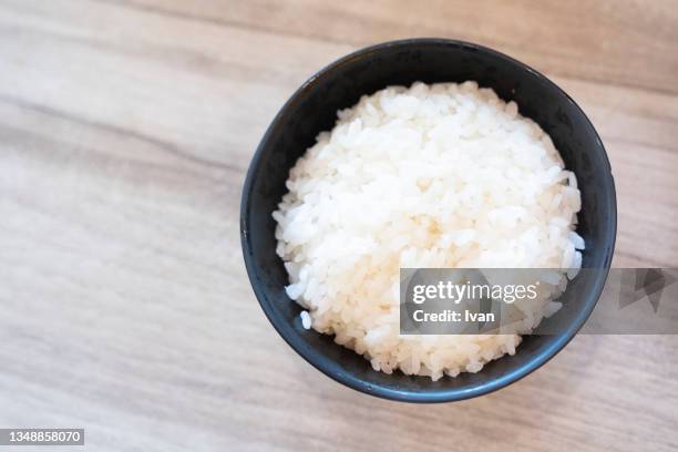 close-up of boiled rice in bowl against wooden background - rice bowl stock-fotos und bilder