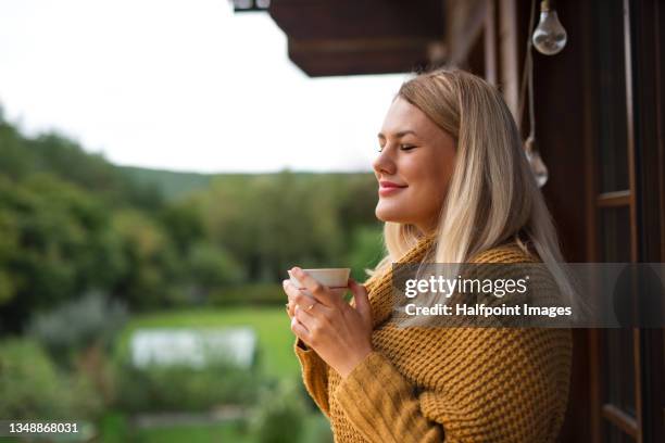 young woman with tea standing outdoors on patio. - té terraza fotografías e imágenes de stock