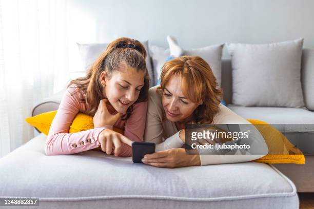madre e hija usando un teléfono inteligente - parents fotografías e imágenes de stock