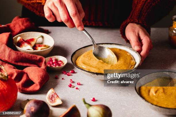 close-up of a woman preparing pumpkin and mango smoothie in kitchen - mango smoothie stock pictures, royalty-free photos & images