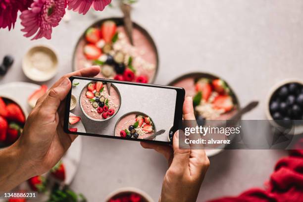 donna che fotografa ciotole di frullato di fragole - hazelnut meal foto e immagini stock