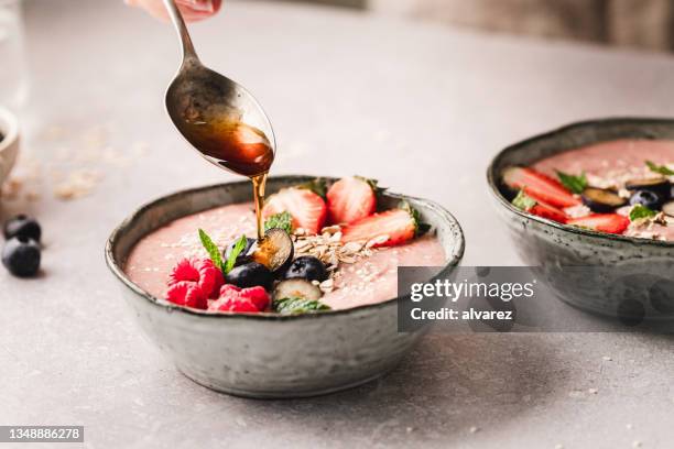 pouring honey over smoothie bowl - smoothie stock pictures, royalty-free photos & images