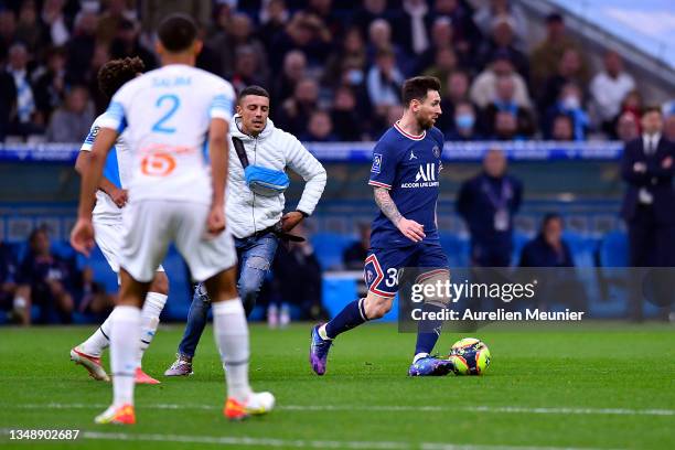 Fan runs on the pitch next to Leo Messi of Paris Saint-Germain during the Ligue 1 Uber Eats match between Marseille and Paris Saint Germain at Orange...