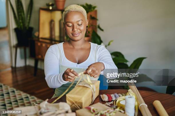 smiling young woman wrapping christmas presents with recycled paper - embrulhar imagens e fotografias de stock