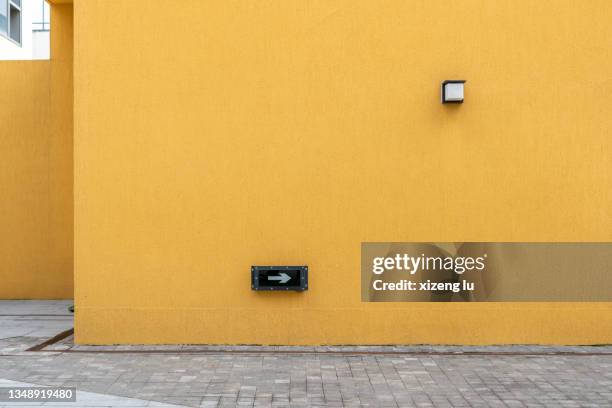 arrow mark on yellow wall - street wall stockfoto's en -beelden