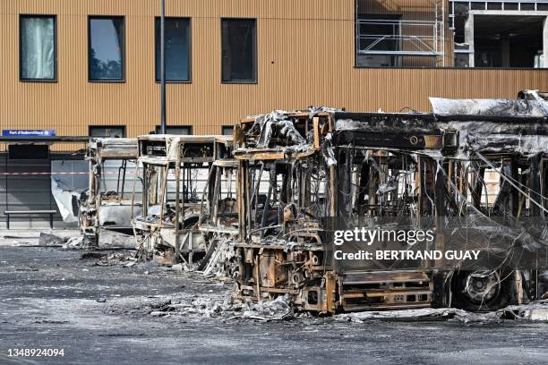 This photograph taken on June 30 shows burnt buses at the Fort d'Aubervilliers bus terminal in front of the future Paris 2024 Olympic swimming venue,...