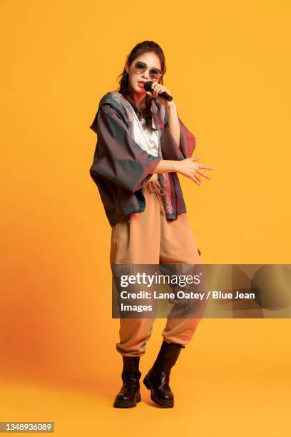 studio shot of fashionable young woman singing - holding microphone stock pictures, royalty-free photos & images