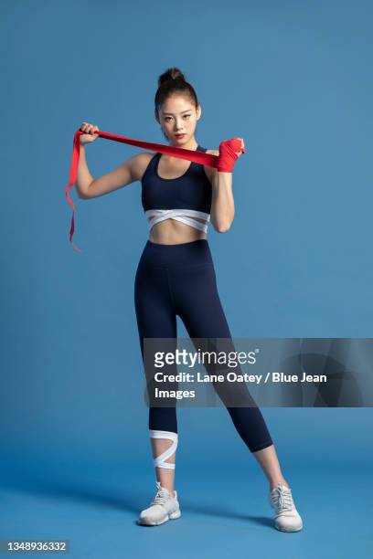 young woman wrapping hands for boxing - asian female bodybuilder stock-fotos und bilder