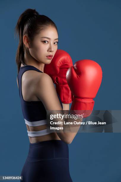 confident young woman in boxing gloves - boxing glove coloured background stock pictures, royalty-free photos & images