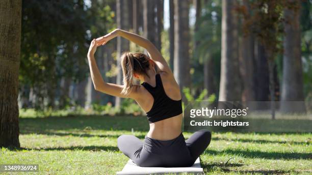 junge frau, die yoga in einem öffentlichen park praktiziert - yoga stock-fotos und bilder
