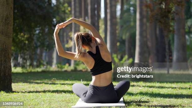 young woman practicing yoga in a public park - ioga imagens e fotografias de stock