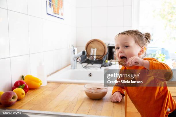 toddler boy eating chocolate mousse in kitchen - chocolate pudding imagens e fotografias de stock