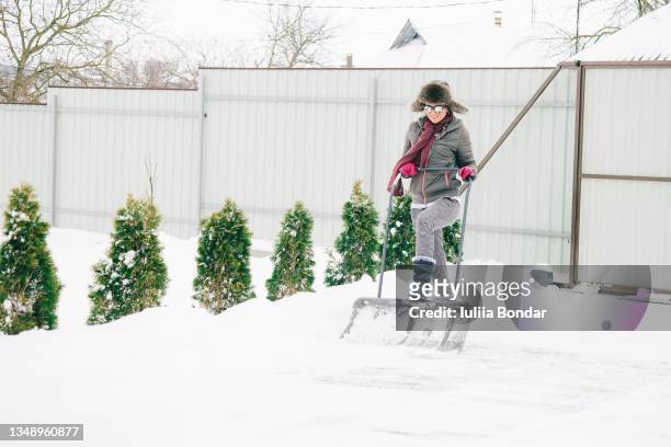 young woman cleaning the snow in the garden - shoveling driveway stock pictures, royalty-free photos & images