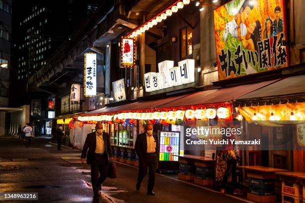 People walk past bars in Yurakucho area on October 25, 2021 in Tokyo, Japan. With Tokyo and its surrounding area seeing a significant drop in...