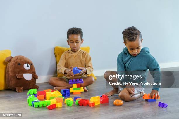 kleine jungen, die mit spielzeugblöcken spielen - kind teddy sitzt stock-fotos und bilder