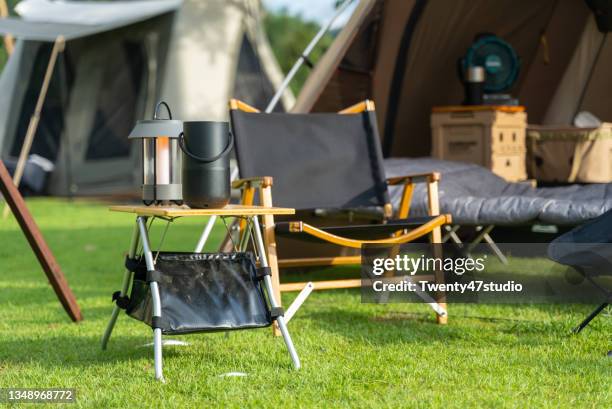 camping folding chairs and wooden table in front the tent - outdoor pursuits ストックフォトと画像