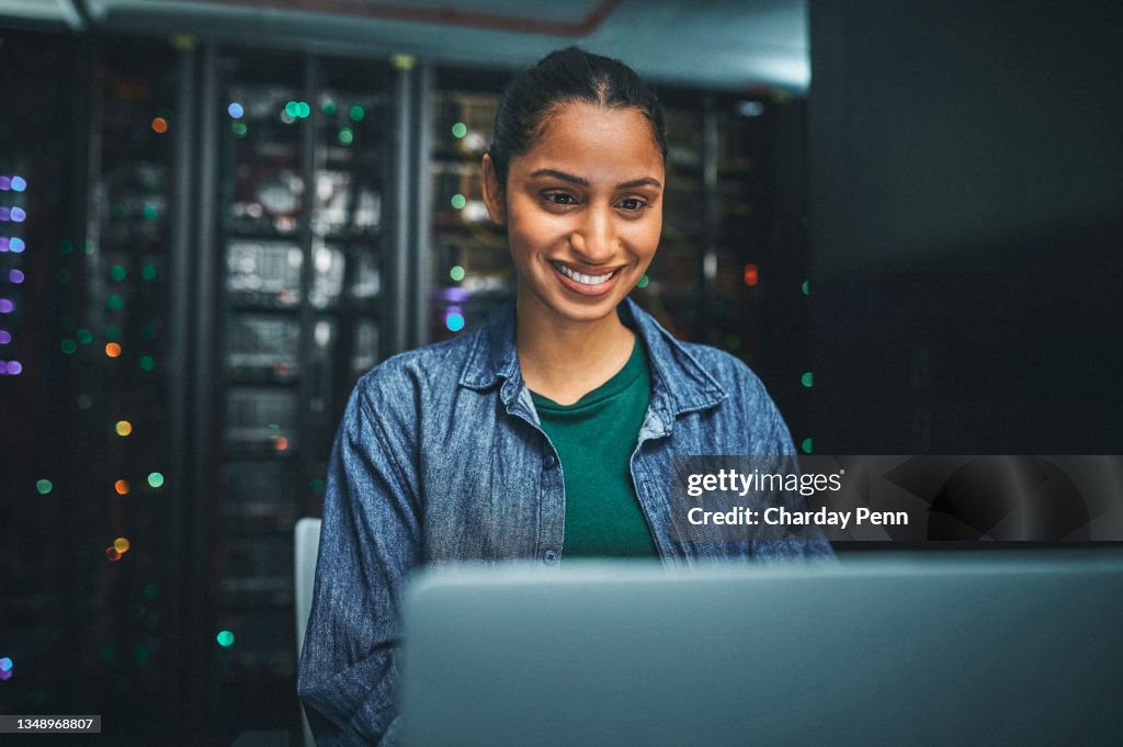 Shot of an female IT technician in a server room and using a laptop