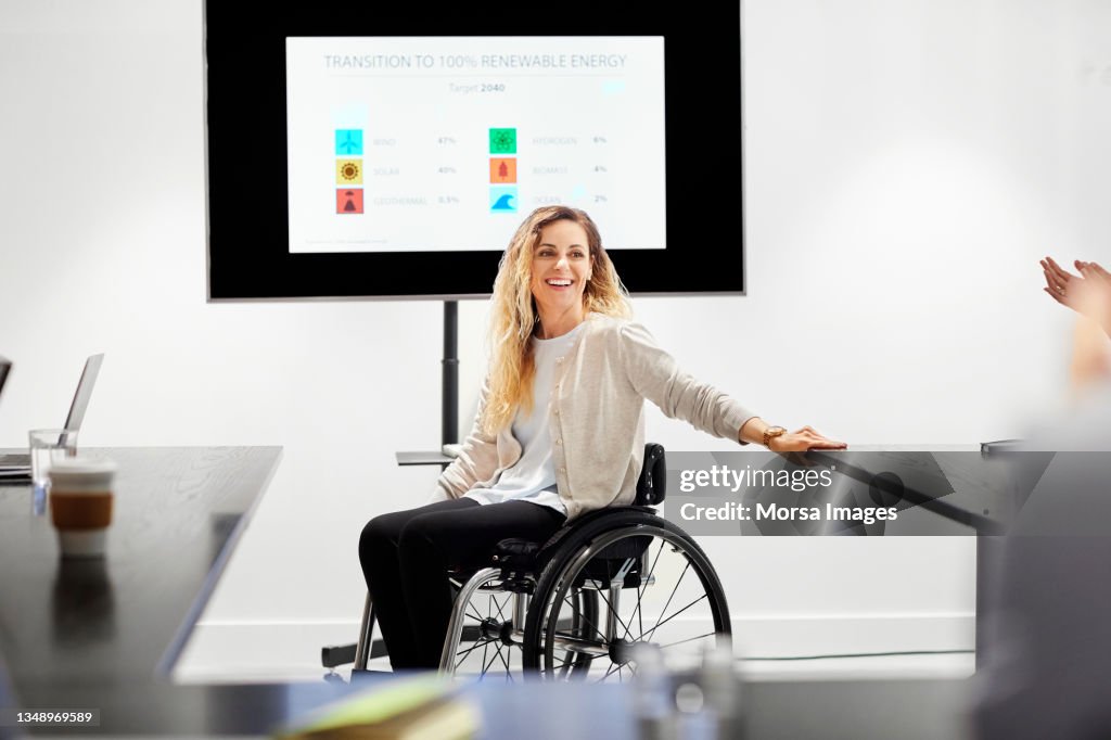 Happy professional on wheelchair in board room