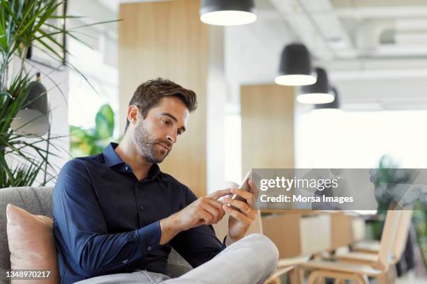 male executive using mobile phone in office - man looking imagens e fotografias de stock