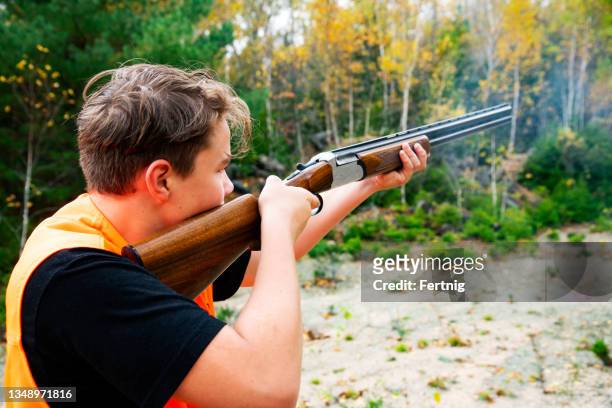 a teen hunter shooting a shotgun in the woods - shotgun stock pictures, royalty-free photos & images