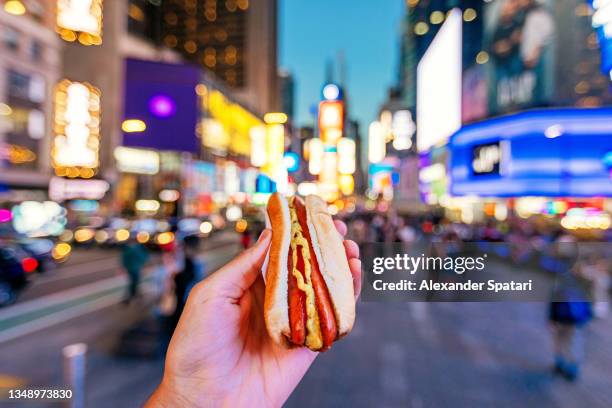 man eating hot dog at times square, personal perspective view, new york, usa - city from a new angle stockfoto's en -beelden