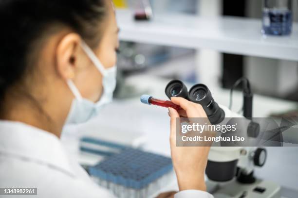 a woman doctor is in the lab holding a test tube - microbiologist fotografías e imágenes de stock