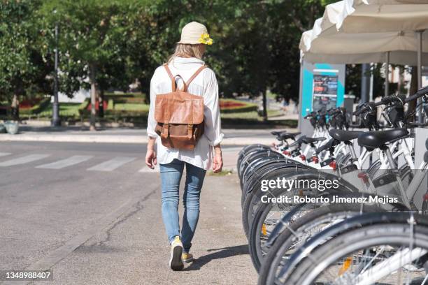 woman renting bicycle at parking station in city - bicycle rental stock pictures, royalty-free photos & images