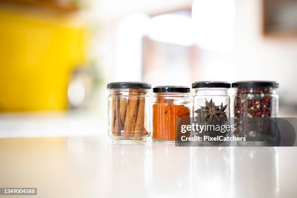 wide shot exotic spices in reused glass jars on kitchen counter - spice jar stock pictures, royalty-free photos & images