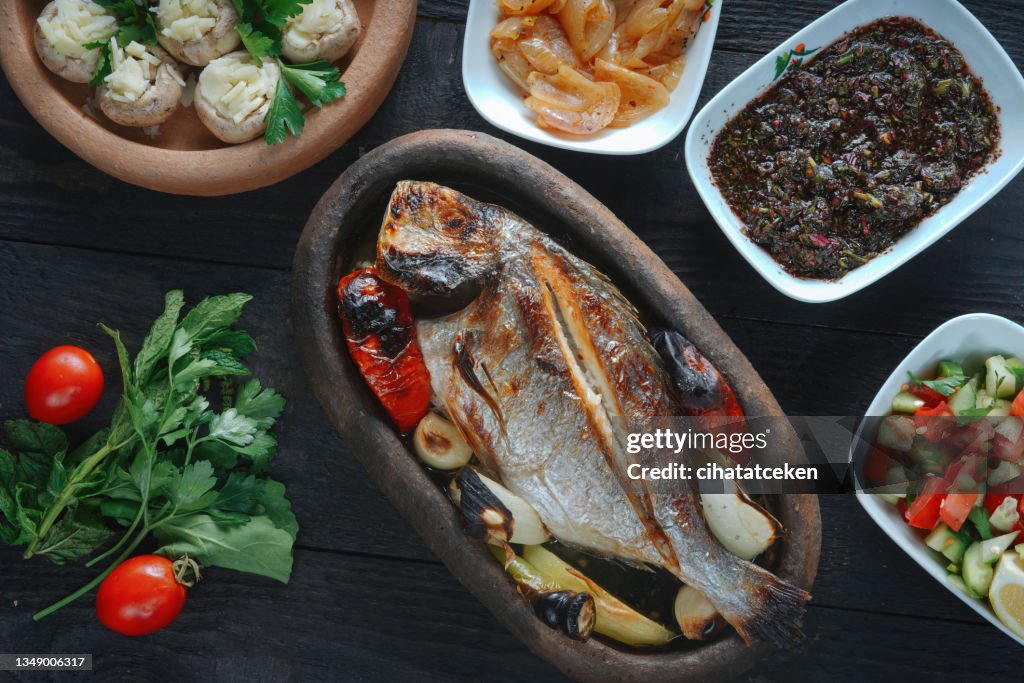 Frischer Fisch auf einem schwarzen Holzbrett. Rohe ungekochte Seebrasse auf schwarzem Teller.