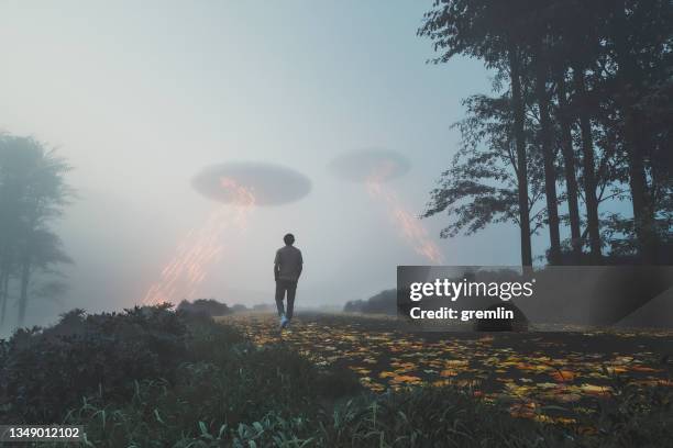 man walking towards ufos on the rural road - extraterrestrial stock pictures, royalty-free photos & images