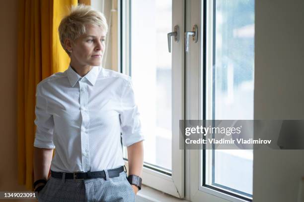 portrait of a homosexual business woman standing next to the window - woman short blonde hair stock pictures, royalty-free photos & images