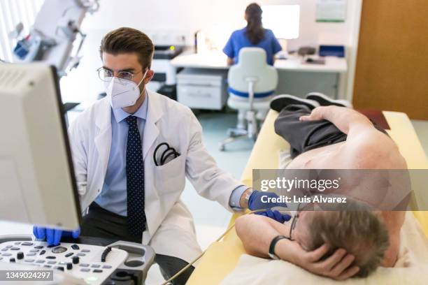 cardiologist doing a echocardiogram test of a male patient in the clinic - echokardiogramm stock-fotos und bilder