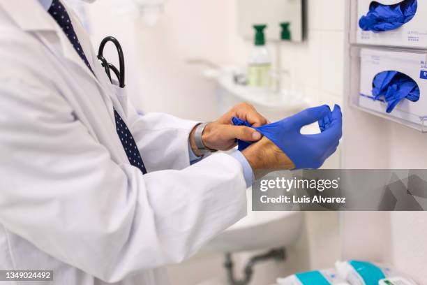 close-up of a doctor wearing protective hand gloves in the clinic - maladie infectieuse photos et images de collection