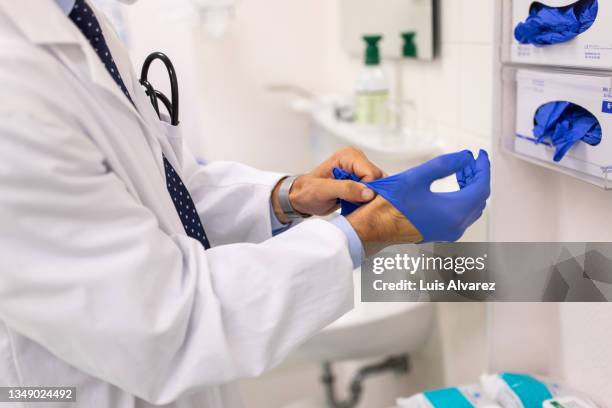 close-up of a doctor wearing protective hand gloves in the clinic - infection prevention imagens e fotografias de stock