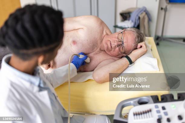senior man having echocardiography test done by a cardiologist in clinic - echokardiogramm stock-fotos und bilder