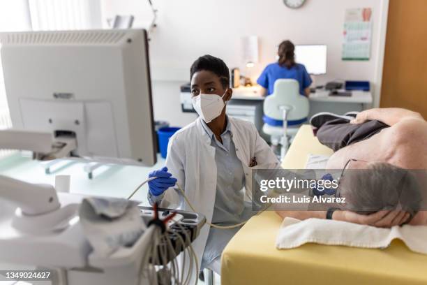 cardiologist doing echocardiogram test of a senior male patient in heart clinic - echokardiogramm stock-fotos und bilder